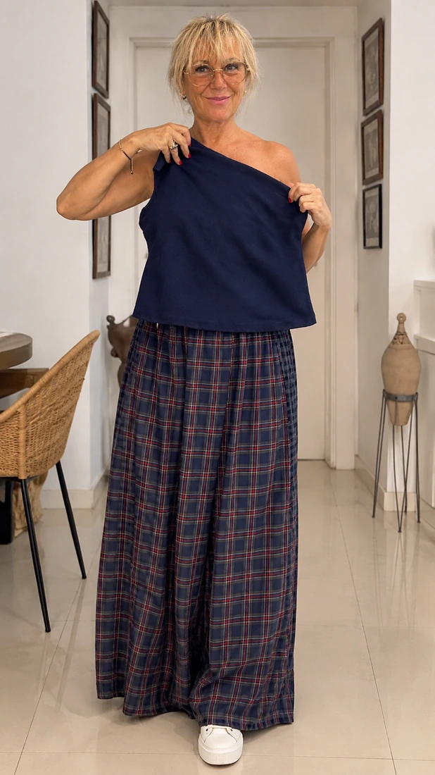 Mercè Paulet con top azul marino de un solo hombro y falda larga de cuadros en azul y rojo